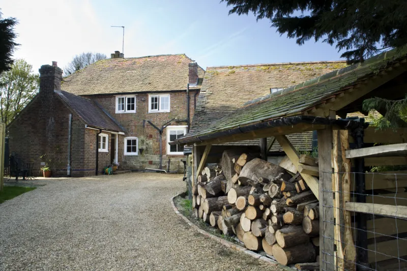 The cottage and log store from the gravel courtyard