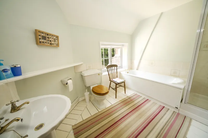 A bright bathroom with bath and separate shower